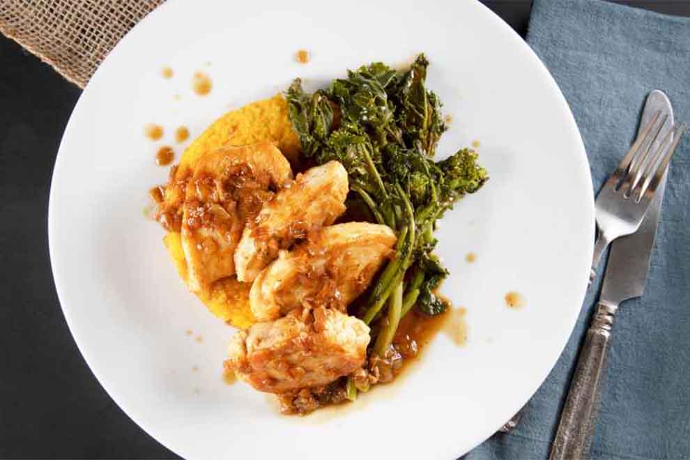 Prato de frango grelhado com molho e vegetais verdes