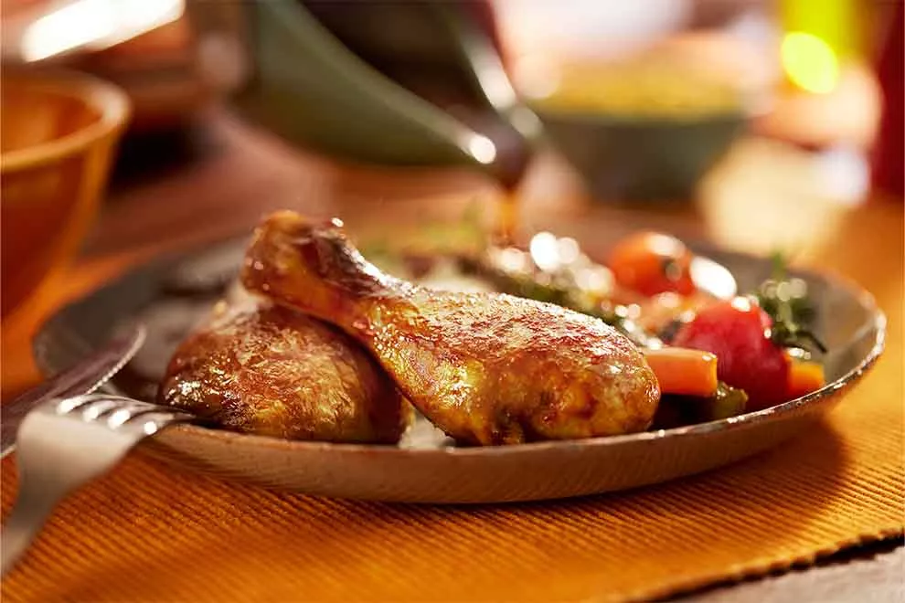 coxa de galeto assado com legumes em cima de um prato de porcelana