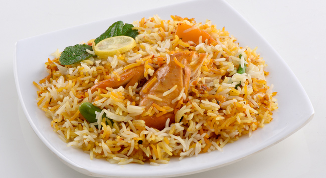 Frango à cubana servido em um prato branco com arroz colorido.