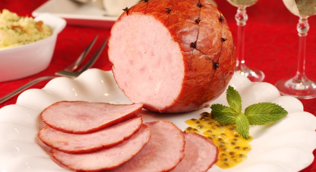 Tender bolinha cravejado servido com molho de maracujá em uma travessa branca.