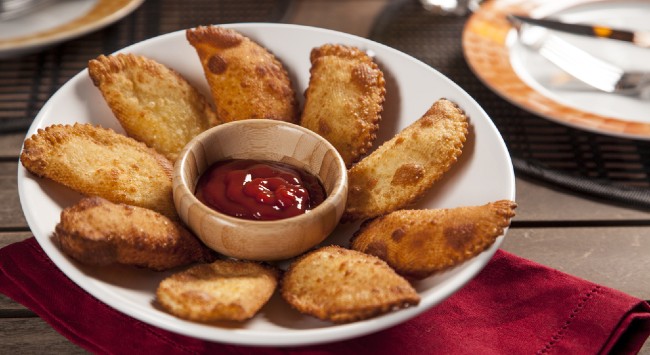 Porção de pastel de linguiça servido em prato branco