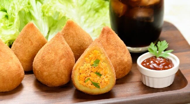 Coxinhas crocantes com recheio de frango ao lado de molho