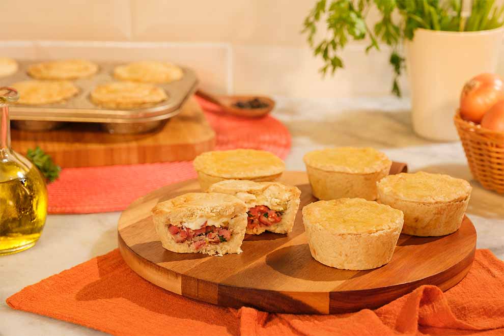 empadinhas de calabresa em cima de uma tábua redonda de madeira e um pano laranja