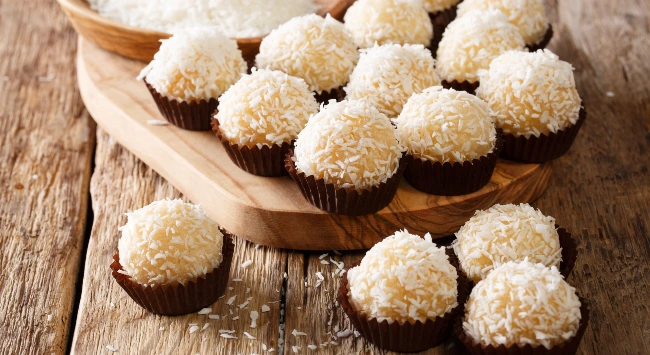 Diversos beijinhos servidos em uma tábua simples de madeira.