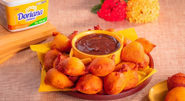 Porção generosa de bolinho de chuva de cenoura servido com brigadeiro cremoso.
