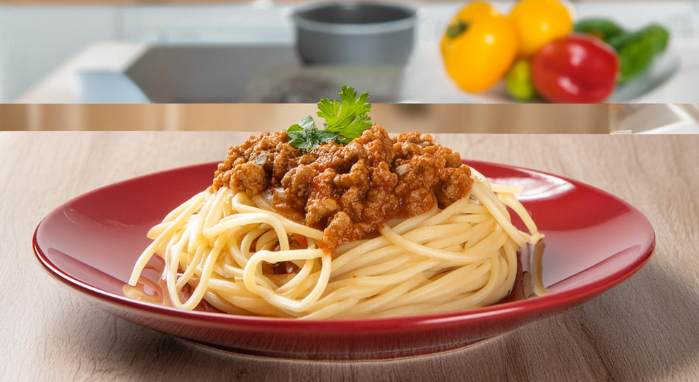 Prato com espaguete a bolonhesa com carne vegetal em um prato vermelho