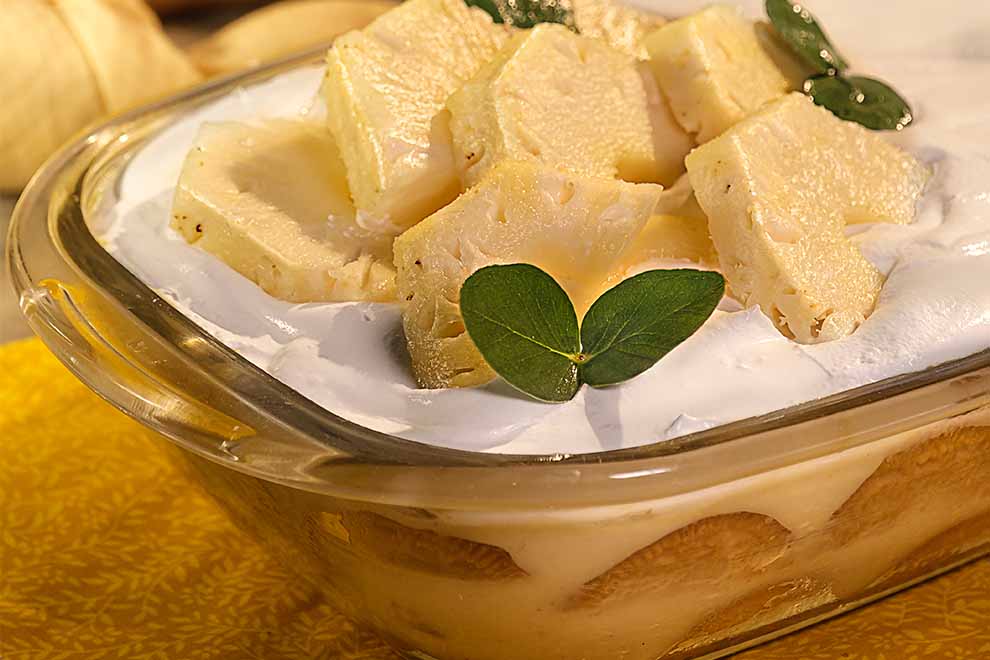 pavê de abacaxi dentro de uma travessa de vidro transparente em cima de um pano amarelo