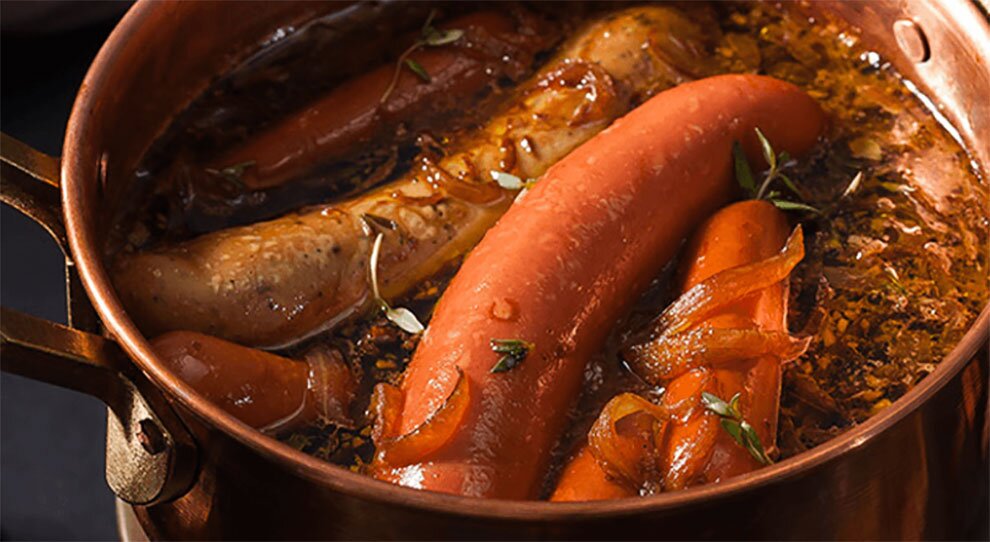Linguiças e cenouras cozidas em panela de cobre