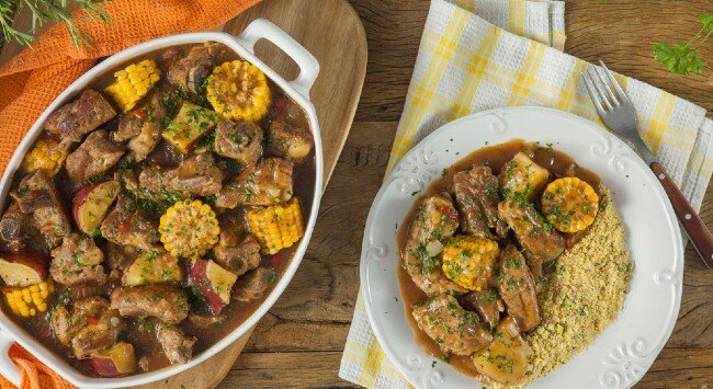 Prato de carne com legumes e milho cozido.