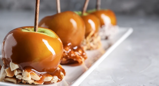 Maçã do amor coberta com caramelo e castanhas.