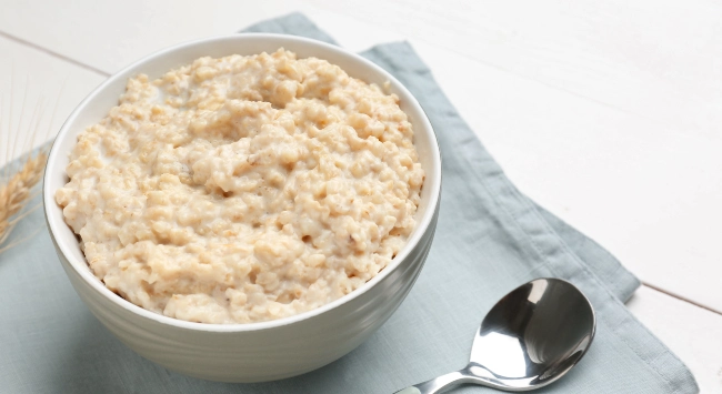 Pote branco, fundo e com uma porção de mingau de aveia.