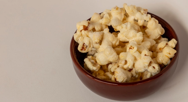 Pote marrom com porção de pipoca doce de leite em pó.