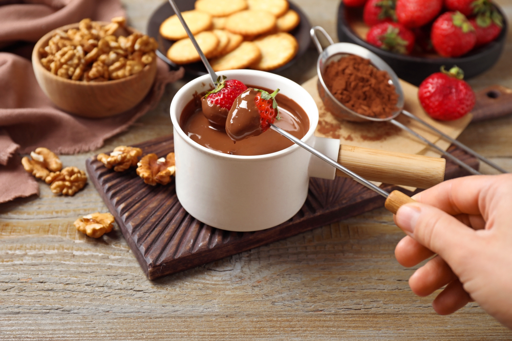 Woman,Dipping,Strawberry,Into,Fondue,Pot,With,Milk,Chocolate,At